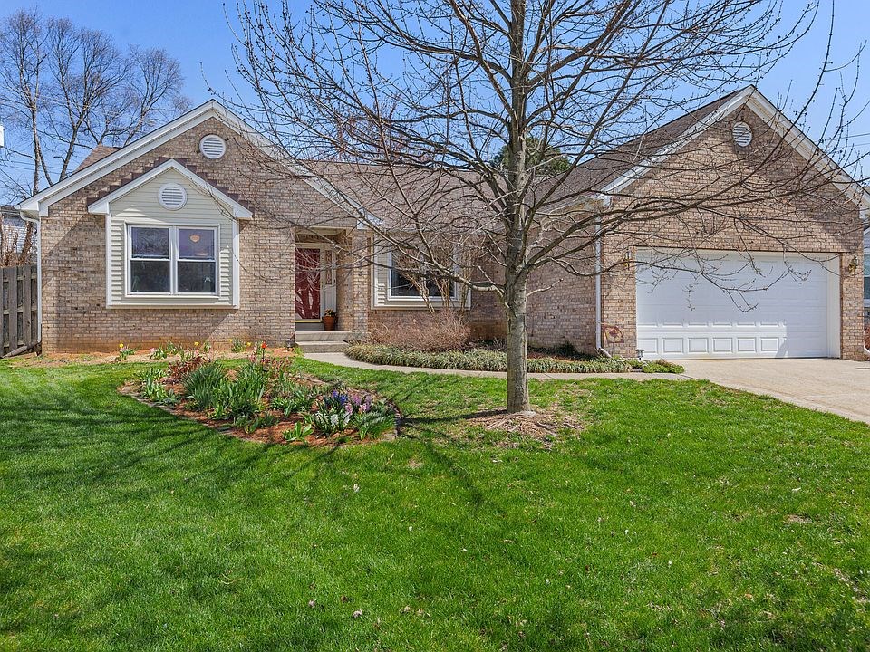 front view of the home spacious yard with beautiful landscaping, a driveway, garage, and walkway to the front door.