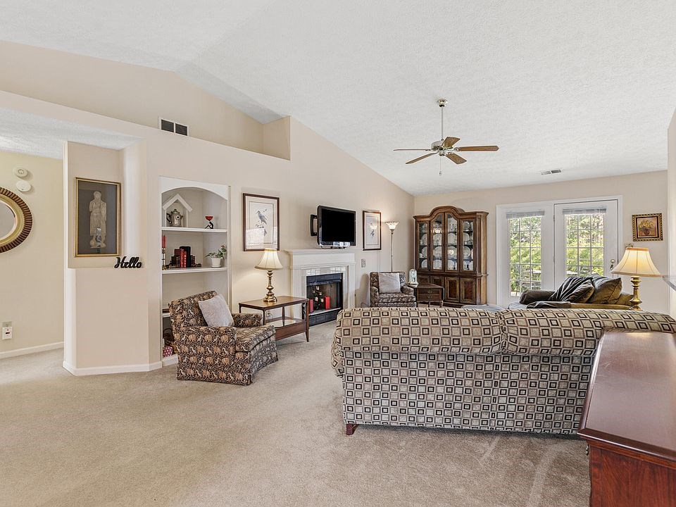 spacious living room area with two glass doors bringing in natural light, the entire space feels bright and open. it also includes a fireplace, carpet, and built-in shelving.
