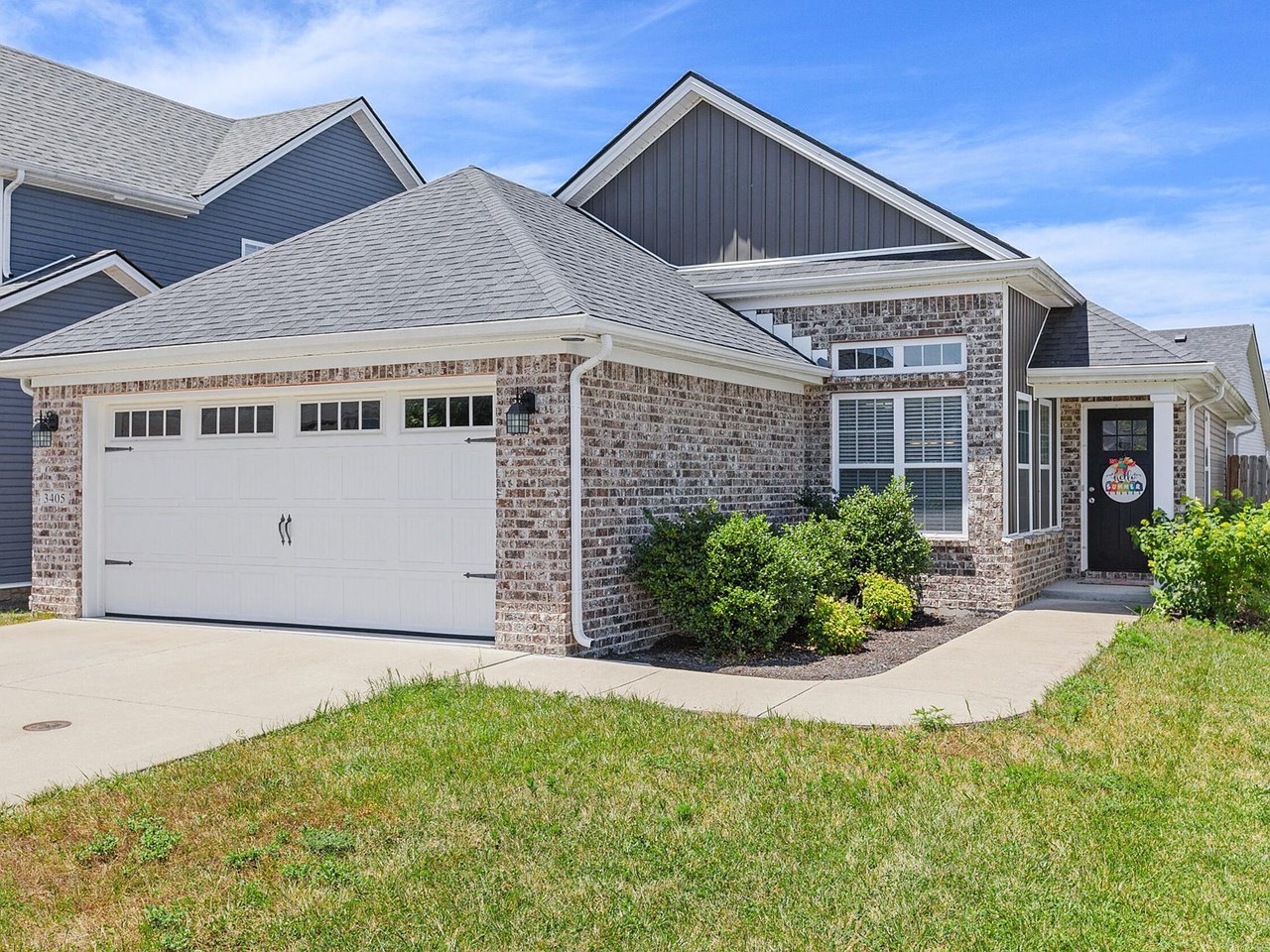 cute ranch style home! this picture shows the entryway as well as the driveway and 2 car garage. it has well-groomed landscape as you head up to the door as well.